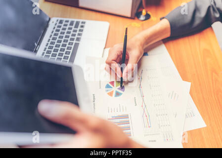 Businessmen are analyzed data from report using smartphone and laptop computer. Stock Photo