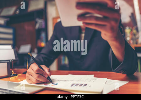 Businessmen are analyzed data from report using smartphone and laptop computer. Stock Photo