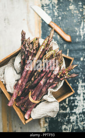 Fresh raw uncooked purple asparagus over wooden tray background Stock Photo