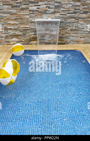 Small modern swimming pool with artificial waterfall Stock Photo