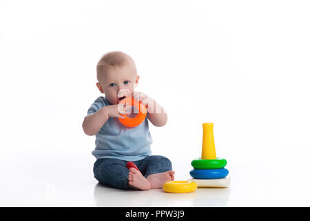 A seven month old baby boy playing with a ring stack toy. Shot in the studio on a white, seamless backdrop. Stock Photo