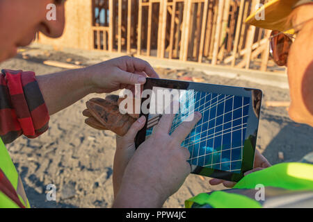 Male and Female Construction Workers Reviewing Building on Computer Pad at Construction Site. Stock Photo