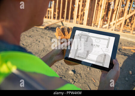 Female Construction Workers Reviewing House Plans on Computer Pad at Construction Site. Stock Photo