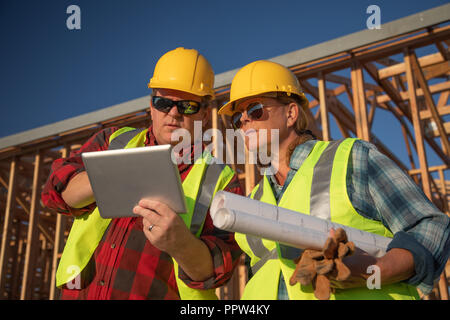 Male and Female Construction Workers Using Computer Pad at Construction Site. Stock Photo