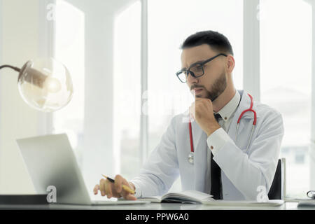 Doctor using laptop and electronic medical record (EMR) system. Digital database of patient's health care and personal information on computer screen. Stock Photo