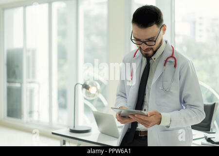 Doctor in hospital working with modern technology for healthy. Friendly man doctor looking and smile for good result of patient data chart. Stock Photo