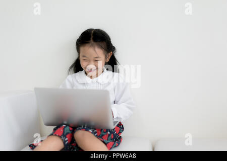 Little asian girl using laptop to studying. Education, free time, technology and internet concept. Stock Photo