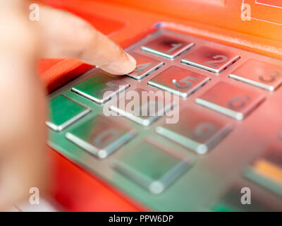 Close up finger inserting password on ATM machine. Hand entering pin code or passcode number on button on bank machine keypad. Stock Photo