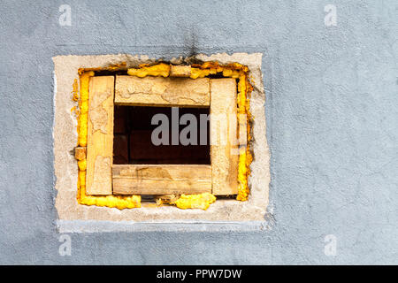 A square hole in a brick wall painted with gray paint. Stock Photo