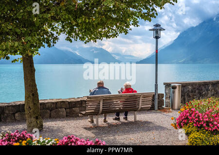 Brienz, Switzerland – September 10, 2015: Along Lake Brienz a promenade was built during World War I where an olderly couple is sitting Stock Photo