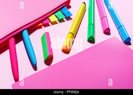 School stationery. Color markers, pens next to the pencil case. Bright stickers in the pencil case. Bright colored elastic band Stock Photo