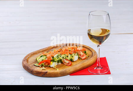 Summer dishes from: red fish, eggs, cucumbers, tomatoes, salad and Peking cabbage next to a glass of white wine. Fine dining at the restaurant Stock Photo