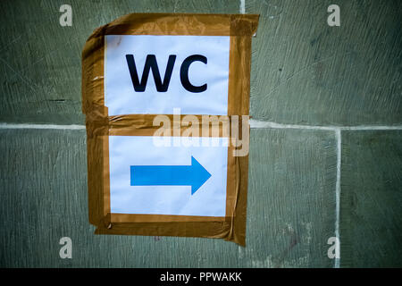 In a park in the Swiss city of Bern paper sheets are taped against a brick wall to indicate the location of the restroom. Stock Photo