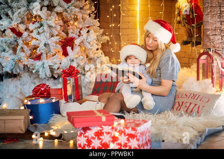 Mother with baby in a hat of Santa Claus in the Christmas room. Stock Photo