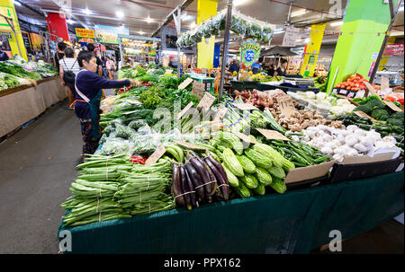 A stall holder arranges Chinese green vegetables at the popular Rusty's Market on Sheridan Street, Cairns, Far North Queensland, Australia