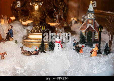 Toy Christmas ceramic miniature with snow-covered city and model of walking people. Small festive village, kids diorama Stock Photo