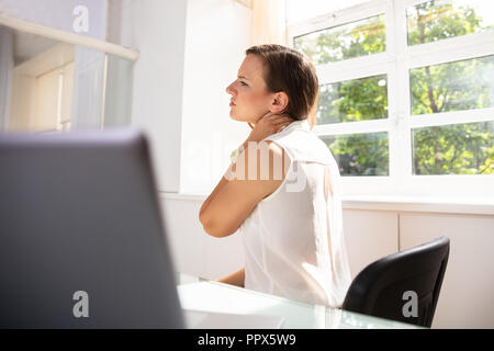 Young Businesswoman Suffering From Neck Pain At Workplace Stock Photo