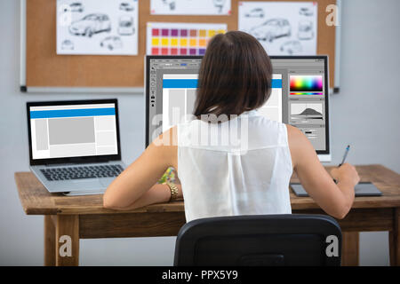 Female Designer Using Graphic Tablet While Working On Computer Stock Photo