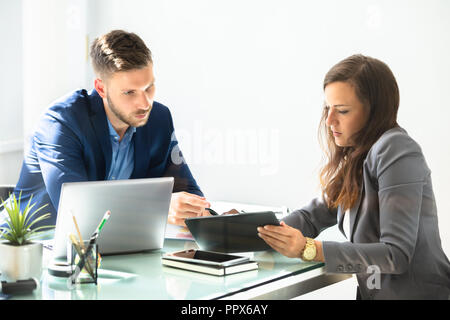 Two Young Businesspeople Using Digital Tablet At Workplace Stock Photo