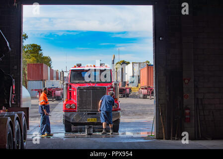 https://l450v.alamy.com/450v/ppx954/two-men-in-work-clothes-washing-the-front-end-of-a-red-prime-mover-semi-trailer-in-a-truck-fleet-yard-in-a-warehouse-entrance-ppx954.jpg