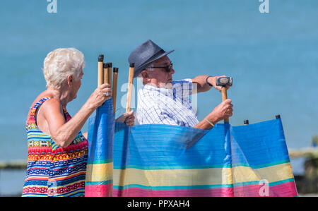 Senior couple putting up a windbreak on a beach in England, UK. Stock Photo