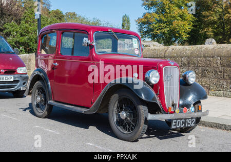 Red Austin Seven (Austin 7) vintage saloon car from 1938 parked by the roadside in the UK. Stock Photo