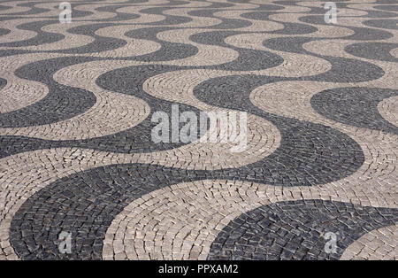 Typical Portuguese black and white stone mosaic calcada pavement - found in Lisbon and other cities in Portugal. Also in Rio de Janeiro, Brazil. Stock Photo