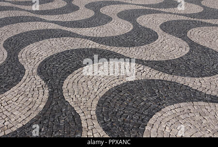 Typical Portuguese black and white stone mosaic calcada pavement - found in Lisbon and other cities in Portugal. Also in Rio de Janeiro, Brazil. Stock Photo