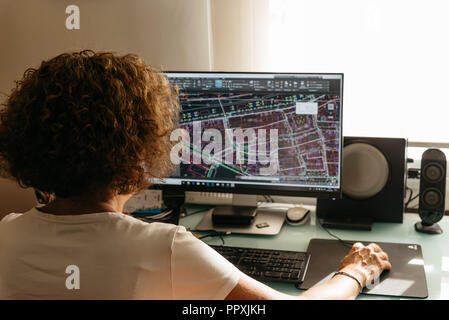 Architect female drawing with cad software designing building. Rear view. She is holding a mobile phone Stock Photo