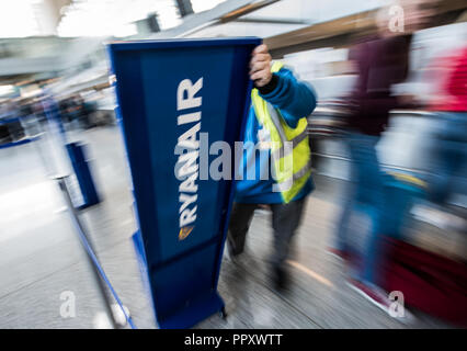 28 September 2018, Hessen, Frankfurt Main: An airport employee moves a Ryanair display. Trade unions in several European countries have called for strikes at low-cost airline Ryanair. In Germany, the pilots of the Cockpit Association (VC) and the flight attendants organized at Verdi participate. Photo: Andreas Arnold/dpa Stock Photo