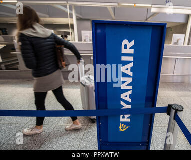 28 September 2018, Hessen, Frankfurt Main: A woman walks past a Ryanair stand with her suitcases. Trade unions in several European countries have called for strikes at low-cost airline Ryanair. In Germany, the pilots of the Cockpit Association (VC) and the flight attendants organized at Verdi participate. Photo: Andreas Arnold/dpa Stock Photo