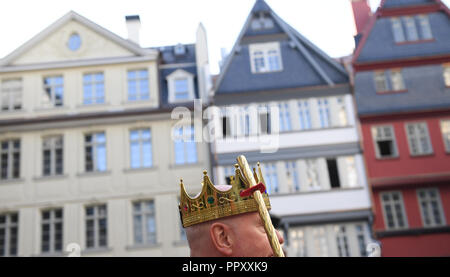 28 September 2018, Hessen, Frankfurt Main: Carl Maria Schulte stands with a metal crown in front of a row of houses on the chicken market in Frankfurt's new Old Town. The foundation stone for the controversial 200 million euro project was laid six and a half years ago. Between the cathedral and the Römer (town hall) 35 houses have been reconstructed in the past years on an area of only seven hectares, partly true to the original. The city celebrates the opening with a three-day festival. Photo: Arne Dedert/dpa Stock Photo