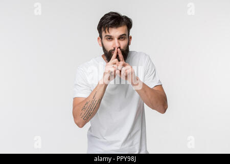 Secret, gossip concept. Young man whispering a secret behind his hand. Businessman isolated on white studio background. Young emotional man. Human emotions, facial expression concept. Stock Photo