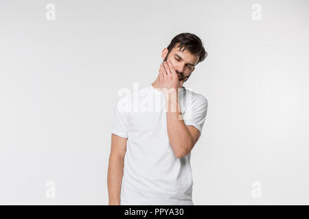Young man is having toothache. Pain concept. Young emotional man. Human emotions, facial expression concept. Studio. Isolated on white Stock Photo