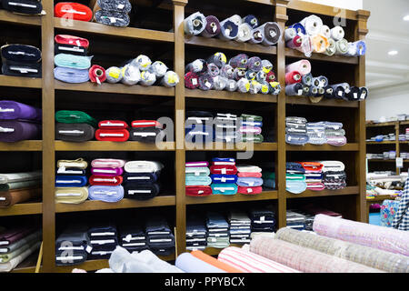 View of cloth rolls of different colors and patterns on shelves in fabric store Stock Photo