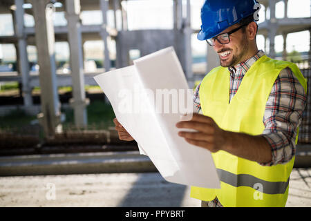 Construction engineer in hardhat with project in hands Stock Photo