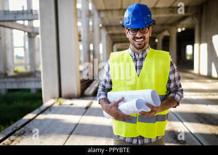 Architect holding rolled up blueprints at construction site Stock Photo