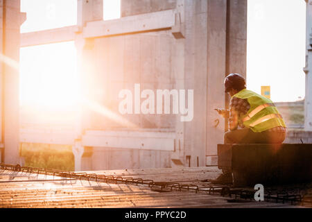 Male architect with blueprints using walkie-talkie Stock Photo