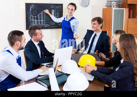 Positive team architectural engineers discussing business project and smiling indoors Stock Photo