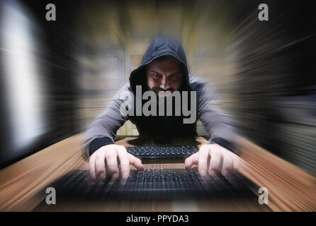 The hacker in the hood sits and works Stock Photo