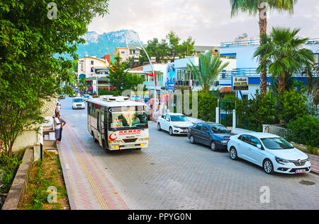 KEMER, TURKEY - MAY 13, 2017: One of the central streets of resort with lush green trees among the cozy family hotels and riding public bus, on May 13 Stock Photo