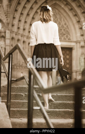 girl teenager going barefoot the stairs and holding shoes outdoors Stock Photo