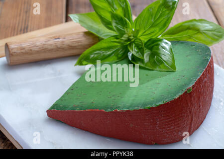 Cheese collection, piece of Dutch green pesto hard cheese with fresh basil close up Stock Photo