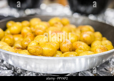 Many small potatoes fried on olive oil on silver frying pan Stock Photo