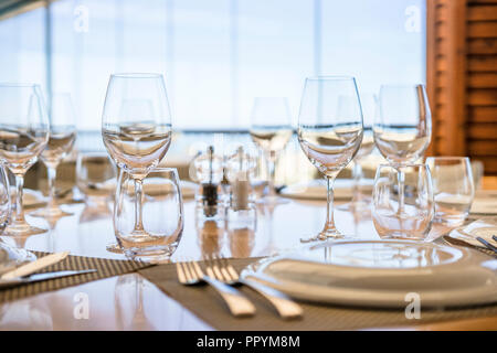 Table with plates, glasses and silverware ready  for lunch in an elegant restaurant Stock Photo