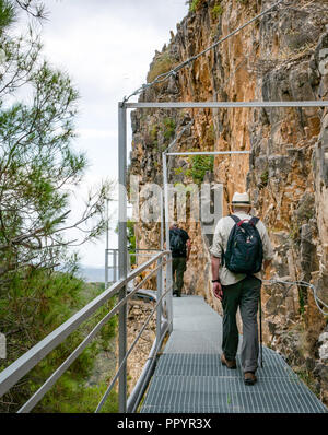 Older men walking on mountain gorge cliff metal walkway, Sierras de Tejeda Natural park, Axarquia, Andalusia, Spain Stock Photo