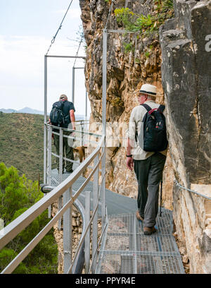 Older men walking on mountain gorge cliff metal walkway, Sierras de Tejeda Natural park, Axarquia, Andalusia, Spain Stock Photo