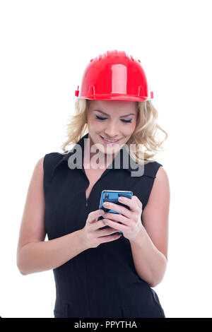 Young engineer woman in red helmet messaging on smartphone isolated on white Stock Photo