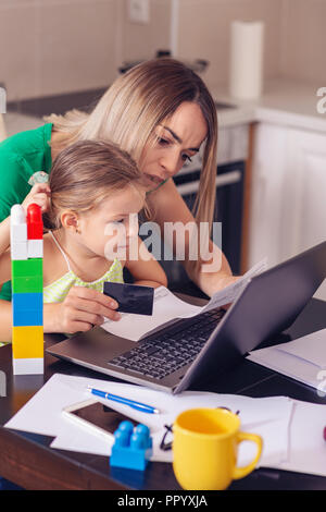 Young mother calculating finances at home with cute daughter Stock Photo