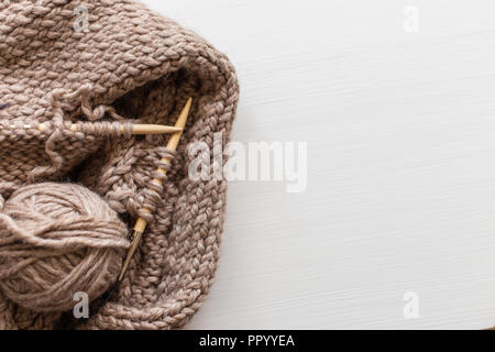 Beige knitting wool and knitting needles on white wooden background. Knitting as a hobby. Accessories for knitting. Stock Photo